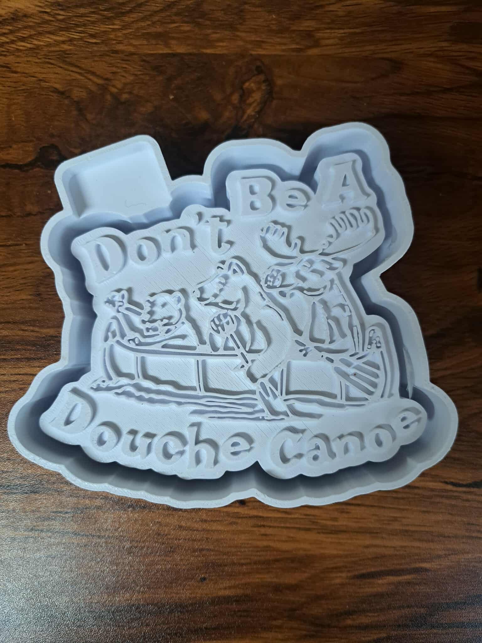 Douche Canoe text on a 3D Housing  on a wooden surface used to produce silicone molds