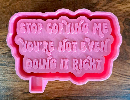 3D silicone mold housing with "stop coping me" text on a wooden surface used to sell silicone molds