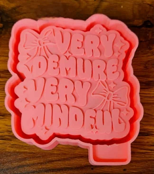 Pink 3d mold housing with text 'VERY  Demure " tested  on a wooden surface used to sell silicone molds