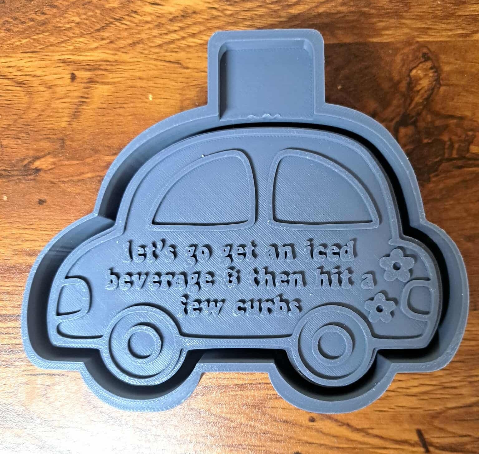 Silicone mold housing shaped like a car with text on a wooden surface