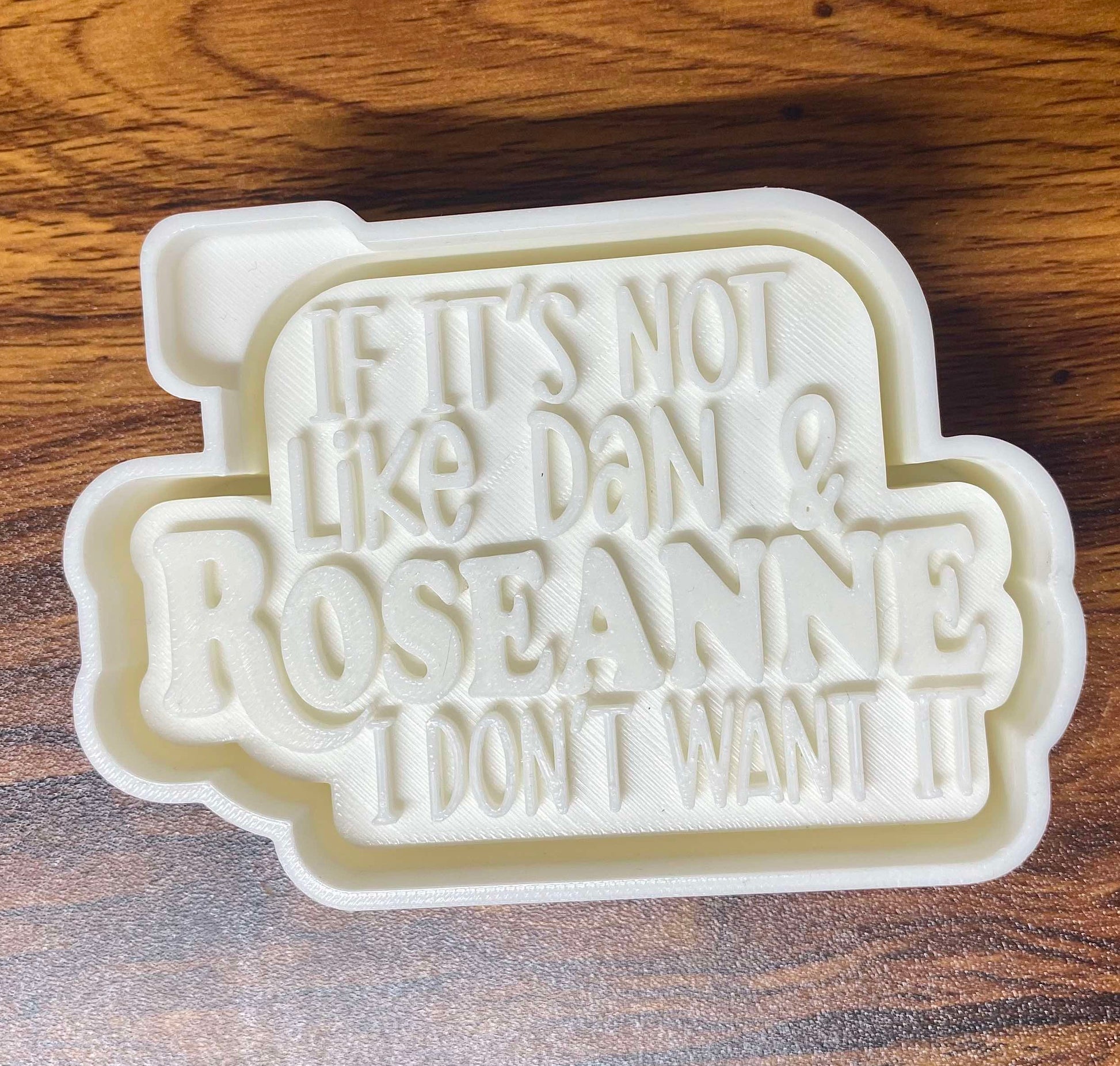 3D mold housing with 'If it's not like Dan & Roseanne, I don't want it' text on a wooden surface to make silicone freshie mold