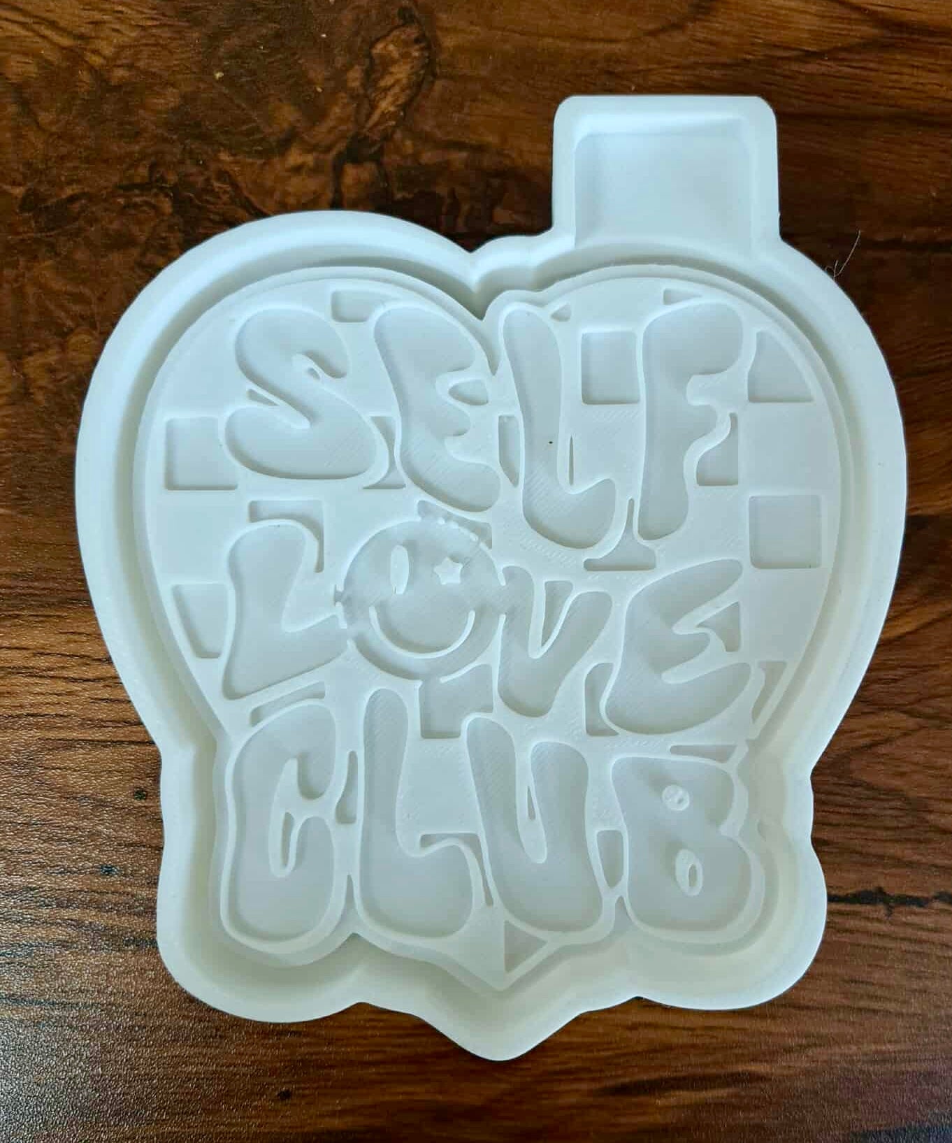 3d housing shaped like a heart with 'SELF LOVE CLUB' text on a wooden surface used to sell silicone molds