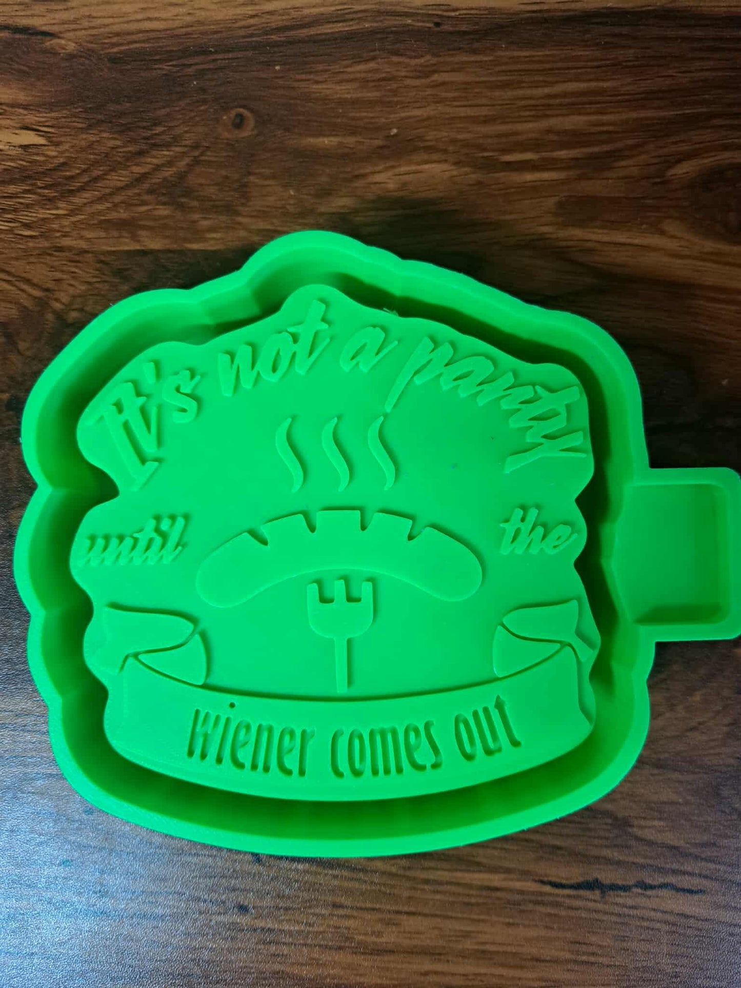 Green 3d housing design  "Its not a party until the wiener comes out" on a wooden surface to make silicone molds