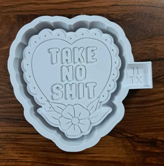 Heart-shaped 3d housing with 'TAKE NO SHIT' text on a wooden counter surface to produce a silicone mold