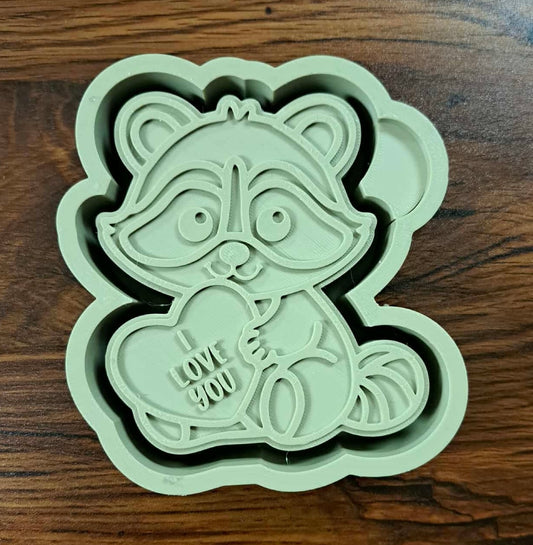 3d shaped mold housing like a raccoon holding a heart with 'I love you' text on a wooden counter surface for silicone mold. 